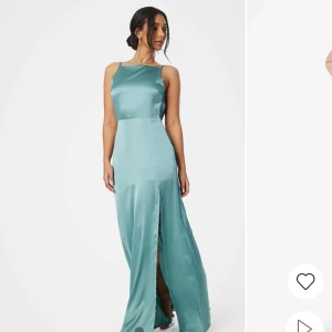 Turkos långklänning i satin - Elegant turkos långklänning i satin med en stilren slits framtill. Klänningen har en vacker öppen rygg och är ärmlös, vilket ger en sofistikerad look. Perfekt för speciella tillfällen som bal eller bröllop. Säljer klänningen i storlek 36 med etikett på. Klänningen är ALDRIG använd. 