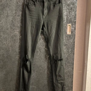 Svarta jeansbyxor från ONLY - Snygga svarta jeansbyxor från ONLY med slitna detaljer vid knäna. Byxorna har en tight passform och är högmidjade, vilket ger en modern look. Perfekta för en trendig stil.