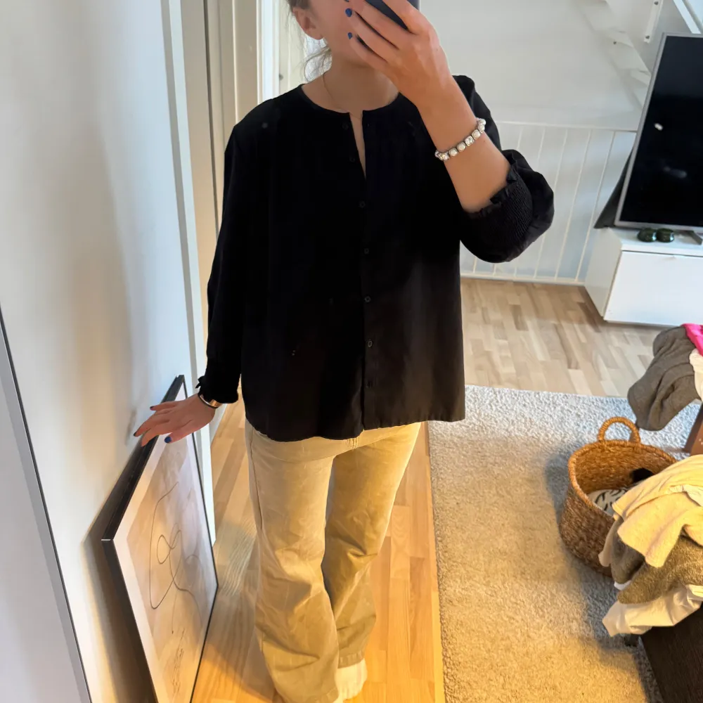 Snygg svart blus med knappar framtill och långa ärmar. Perfekt för en stilren look. Blusen har en rundad hals och en lös passform som ger en bekväm känsla. Inspirerad av Isabell marant . Paidat.