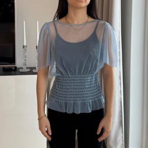 Blå transparent blus  - Säljer en söt blå transparent blus från Pure Friday med puffiga korta ärmar och elastisk midja. Strl XS. Passar bra till både jeans och kjol. Använd 2 gånger.