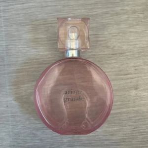 Parfym från Ariana Grande - Nypris : 850 kr  Doftfamiljen är blommig, gourmand, fruktig. Toppnoter= Päron, hallon Hjärtnoter= Ros, Kokosnöt Basnoter= Mysk  Använd enstaka gånger och nästan full.  Parfymen beskrivs följande: ”beroendeframkallande topp med bubblande vitt päron, fruktiga vildhallon och ett lekfullt hjärta av rosblad och kokos. Basen bjuder på fyllig och sammetslen mysk som adderar kaxighet, toppad med sötman i en krispig macaroon.”