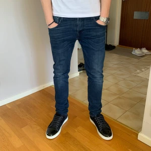 Replay anbass jeans - Snygga mörkblå jeans från Replay med en slim passform. Jeansen är i använt skick och har lite slitage på lappen på baksidan samt vid skrevet som visat. Modellen är 177 cm och väger 62 kg. (Nypris 1000kr) Mitt pris 349 kr. 