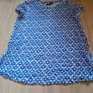 Nwot Blå mönstrad blus från Ellos - Säljer en blus från Ellos med blått och vitt mönster. Blusen har korta ärmar och rund halsringning. Tillverkad i mjuk bomull, perfekt för en färgglad och bekväm stil. Oanvänd 