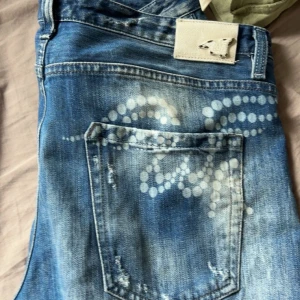 Replay, We Are Replay - Säljer ett par blå replay jeansbyxor från 24K med slitningar och unikt prickigt mönster på bakfickan. Byxorna har orange knapp och detaljer, samt klassisk femficksdesign. Perfekta för dig som gillar en avslappnad och trendig stil, skriv angående frågor osv.