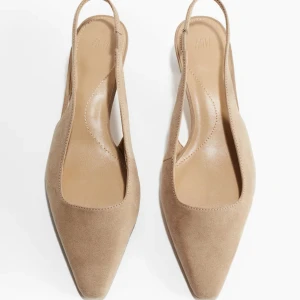 Beige slingback skor med spetsig tå - Snygga beige slingback skor med spetsig tå i mocka-look. Skorna har öppen häl och en elegant, minimalistisk design som passar perfekt till både jeans och klänning.