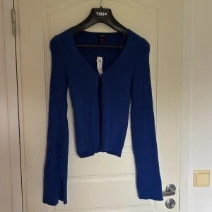 Blå ribbad kofta från Lindex - Säljer en blå ribbad kofta från Lindex i storlek M. Koftan har v-ringning, långa ärmar och är tillverkad i ett stretchigt material. Perfekt att slänga över en topp när det är lite kyligare ute.