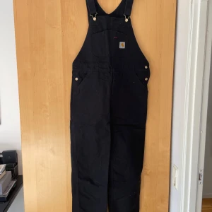 Carhartt overall - Ovanliga, speciella, men väldigt snygga Carhartt workingpants/overall.  Storleken är 34-midja och 34-längd, tillika storlek Large. Köpta för 2600 kronor. Aldrig använda.