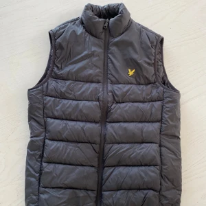 Svart väst från Lyle & Scott - Säljer en grå dunväst från Lyle & Scott. Skick 8,5/10 Västen har hög krage och dragkedja framtill. Perfekt för dig nu på vår/sommaren och enkel att matcha med olika outfits. Köpren står för frakt 🚚 skriv för frågor