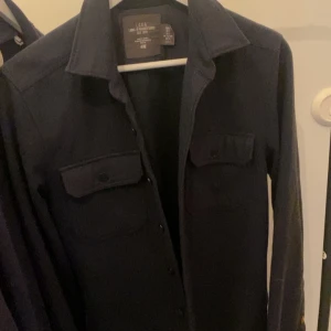Hm Overshirt  - Bra skick förutom att en knapp saknas vid ärmen längst ut, pris går att diskutera. Den är mörkblå i assköng material perfekt i väder som det är just nu