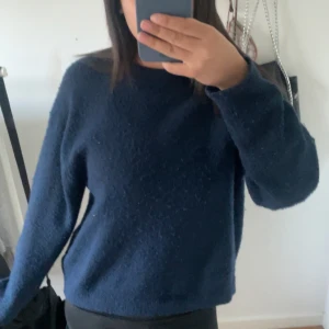 Mörkblå stickad tröja - Mysig mörkblå stickad tröja med rund halsringning och långa ärmar. Perfekt för kyligare dagar och enkel att matcha med olika outfits.
