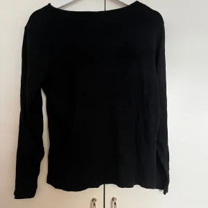 Svart ribbad långärmad topp - Säljer en svart långärmad topp i ribbat material. Tröjan har en enkel och stilren design med rund halsringning och smal passform. Perfekt att matcha med jeans eller kjol för en clean look.