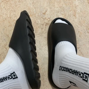 Svarta Slides perfekta för sommaren  - Säljer ett par svarta slides med chunky, räfflad sula. De är tillverkade i syntetmaterial och har en enkel, stilren design utan synliga detaljer. Perfekta för sommaren och autfiten