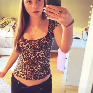 Leopardmönstrad topp från Nelly - Säljer en snygg leopardmönstrad topp från Nelly med korta ärmar och djup rundad halsringning. Toppen är figurnära och passar perfekt till både jeans och kjol. Materialet är mjukt och stretchigt för en bekväm passform.