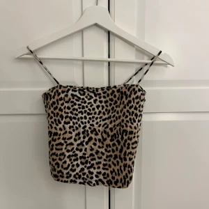 Leopardmönstrad topp - Säljer en snygg leopardmönstrad tubtopp med tunna axelband. Perfekt för dig som vill sticka ut med ett djurmönster. Toppen har en croppad passform och är superenkel att matcha med både jeans och kjol.