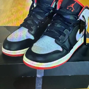 Nike Air Jordans i svart, grått och rött - Säljer ett par Nike Air Jordans med svart och grå ovandel, röda detaljer och vit sula. Skorna har klassisk snörning och rund tå. Perfekta för dig som gillar streetwear och vill sticka ut med snygga sneakers.