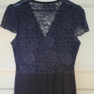 Mörkblå maxiklänning stretchig 40 - Elegant mörkblå långklänning med överdel i spets och v-ringning. Kjolen är slät och har tungt och snyggt fall. Smickrande modell! Perfekt för bal eller festliga tillfällen. Märke Wal G. Köpt på Zalando. Använd 2 ggr bara. Storlek 40