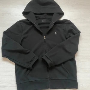  Polo Ralph Lauren zip hoddie  - Säljer en svart hoodie från Polo Ralph Lauren med dragkedja och broderad logga på bröstet. Tröjan har huva och två fickor framtill. Perfekt för en avslappnad och stilren look. Strolek M passe S fraktar inom 24 timmar 