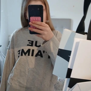 Beige tröja med text från Gina Tricot - Säljer en beige tröja från Gina Tricot med svart text 'JE T'AIME' på framsidan. Tröjan har rund halsringning och långa ärmar, perfekt för en avslappnad stil.