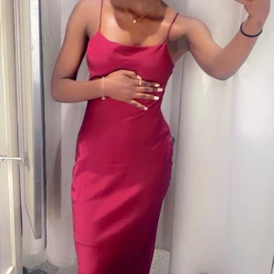 Vinröd långklänning med smala axelband - Säljer en elegant vinröd långklänning med smala axelband och lätt draperad urringning. Klänningen har en figurnära passform och är perfekt för speciella tillfällen. Enkel och stilren design som framhäver siluetten.