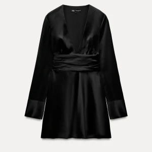 Svart satin klänning från Zara - Supersnygg svart kortklänning i satin från Zara med djup v-ringning och långa ärmar. Klänningen har markerad midja och en elegant, glansig finish som ger en lyxig känsla. 