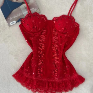 Röd paljettkorsett med spetsdetaljer - Supersnygg röd korsettopp med tunna axelband, paljetter och broderade detaljer framtill. 🤍