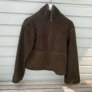 Grön teddyjacka  - Mysig grön teddyjacka från H&M i storlek S. Jackan har hög krage, dragkedja framtill och två stora fickor. Den är i jättefint skick.