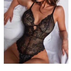 Oanvänd Svart spetsig korsett/body med tunna band - Säljer en OANVÄND svart korsett med tunna axelband och vacker spetsdetalj. Modellen har djup v-ringning, genombruten spets och dekorativa kanter. Tillverkad i bomull och elastan för en bekväm och följsam känsla. Perfekt för dig som vill ha en snygg och feminin look.