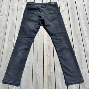 Nudie grim Tim dark cove - Snygga svarta jeans från Nudie Jeans i rak modell. Jeansen har klassiska fem fickor, svarta sömmar och diskret logga på bakfickan. Tillverkade i 99% bomull och 1% elastan för lite stretch. Modell grim Tim. Färg Dark cove. NYPRIS 1600 KR. Andvände 2-3 gånger nytt skick
