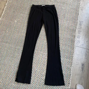 Svarta ribbade byxor från Name It - Svarta ribbade, lågmidjade byxor från Name It i stretchigt material. Byxorna har bootcut-modell med utsvängda ben och elastisk midja för skön passform. 