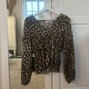 Leopardmönstrad blus från missäy - Har endast andvänt få gånger, ungefär ca 3 gånger. Säljer en snygg blus från missäy med leopardmönster i bruna och svarta toner. Blusen har v-ringning, långa ärmar och cool snörningsdetalj framtill som ger en unik look. Perfekt för dig som vill sticka ut med djurmönster och trendiga detaljer. Detta är en fantistiskt och cool tröja som passar till många stilar, kontakta om funderingar 💕