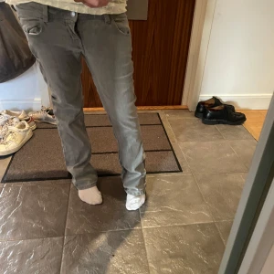 Gråa raka jeansbyxor - Säljer ett par gråa jeansbyxor med klassisk femficksdesign och raka ben. Byxorna har normal passform och är tillverkade i mjukt jeanstyg, perfekta för en avslappnad stil. Passar dig som gillar enkel och stilren look.