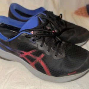 Asics Gel-Pulse 13 GTX Löparskor Svart/Blå Strl 41 - Säljer ett par Asics Gel-Pulse 13 GTX löparskor. Skorna är i färgen svart och blå med röda detaljer. Perfekt för löpning i alla väder tack vare GORE-TEX membranet. I mycket bra  skick .