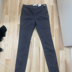 Randiga skinny byxor från L.O.G.G. - Snygga svartvita randiga byxor från L.O.G.G. i storlek 38. De har en tight skinny passform, hög midja och dragkedja i sidan. Perfekta för dig som gillar stilrena detaljer och smal siluett.