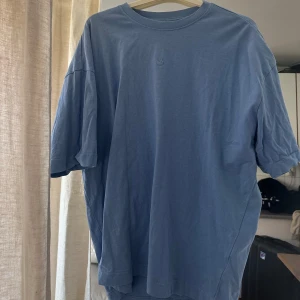 Blå oversized t-shirt med smiley - Säljer en ljusblå oversized t-shirt i bomull med broderad smiley på bröstet. 