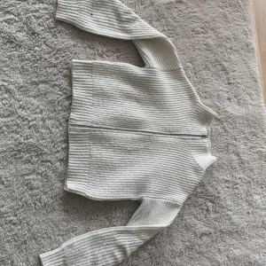 Vit ribbad kofta från Kappahl - Vit ribbstickad kofta från Kappahl i storlek 134/140. Koftan har dragkedja framtill, hög krage och långa ärmar. Perfekt för lager-på-lager och enkel att matcha med olika outfits.