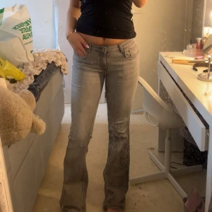 Grå bootcut jeans med låg midja - Säljer ett par snygga grå jeans med bootcut-modell och låg midja. Jeansen har klassiska fickor fram och bak, bälteshällor och dragkedja. Perfekta för dig som gillar en avslappnad men trendig look.