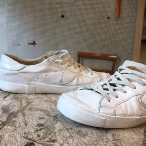 Vita Philippe Model i skinn med snörning - Snygga helvita sneakers i skinn med klassisk design och rund tå. Skorna har vita snören och platt sula, perfekta för en clean och stilren look. Passar till det mesta och är lätta att matcha med olika outfits.