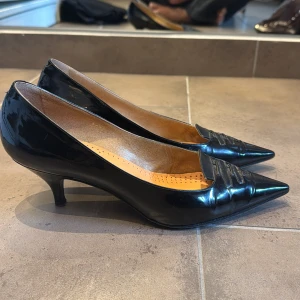 Svarta kitten heels - Snygga svarta klackar i lackat skinn från Rocco med spetsig tå och låg klack. Skorna är köpta second hand! Storlek 37 - 37 1/2 