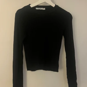Svart ribbad tröja från NA-KD - Säljer en svart, ribbstickad långärmad tröja från NA-KD. Tröjan har en tight passform och är croppad i modellen. Tröjan passar en xxs men även en small. Pris kan alltid diskuteras 🫶🏼