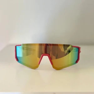 Sportiga barn spegelglasögon  - Säljer ett par futuristiska barn sportglasögon med spegelglas i guld och grönt. Ramen är röd framtill och svart på skalmarna, med en cool, kantig design. Perfekta för dig som vill sticka ut på träningen eller cykelturen😎