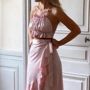 Ljusrosa satin halterneck linnetopp - Supersöt ljusrosa linnetopp i satin från Obsession Stockholm, helt ny! Toppen har halterneck med smala knytband, volangkant nertill och en glansig finish som ger en lyxig känsla. Perfekt för varma dagar när du vill sticka ut lite extra💕