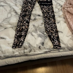 Leopardmönstrade leggings från Stronger - Snygga leopardmönstrade leggings från Stronger med svart resår i midjan där loggan syns. Tight passform och stretchigt material som passar perfekt till träning eller chill. Färgerna går i beige, svart och brunt. Pris kan diskuteras 