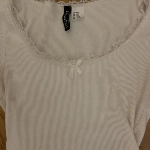 Vit ribbad topp med spets och rosett - Supersöt topp från h&m, kommer ej till användning längre, fint skick ❣️❣️kom privat för bilder på!!💝💝