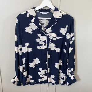 Mörkblå mönstrad skjorta & Other Stories - Snygg mörkblå skjorta från & Other Stories med vitt abstrakt mönster. Skjortan har klassisk krage, knäppning framtill, bröstficka och långa ärmar med vita passpoaler. Perfekt för dig som gillar unika prints och en avslappnad men stilren look. Tyg i blandning av modal och viskos. Nypris cirka 1000 kronor. Säljes för 150 kronor.