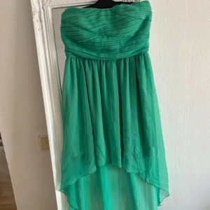 Grön axelbandslös klänning från Vila - Snygg grön axelbandslös klänning från Vila med draperad överdel och asymmetrisk nederkant. Storlek S