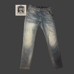 Replay ANBASS Hyperflex ljusblå jeans - Snygga ljusblå jeans från Replay Hyperflex med klassisk femficksdesign och diskreta slitningar. Jeansen har raka ben och normal passform, tillverkade i stretchigt denim för extra komfort. Perfekta för dig som gillar en avslappnad men stilren look.