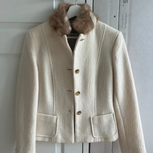 Beige ulljacka med päls Max Mara - Snygg beige jacka från Max Mara Weekend med klassisk krage i ljusbrun päls, guldknappar och två fickor framtill. Jackan är figursydd och har lång ärm, perfekt för dig som gillar en stilren och lyxig look. Köptes av min mamma för några år sen men är knappt använd eftersom det passat inte min stil. Nypris 6000kr