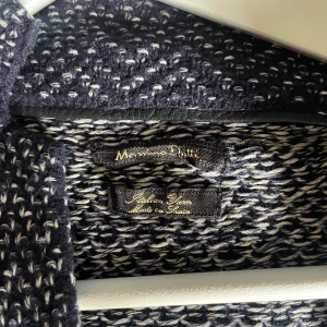Mörkblå stickad cardigan jacka Massimo Dutti - Säljer en mörkblå och vit stickad cardigan jacka från Massimo Dutti. Jackan har ett snyggt mönster, två stora fickor fram och knäppning med knappar. Tillverkad av italienskt garn och har en avslappnad, lite loose passform.