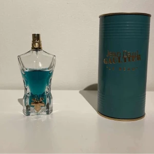 Jean Paul Gaultier Le Beau EdT 75ml - Jean Paul Gaultier Le Beau Eau de Toilette 75ml. Flaskan är formad som en manlig torso i klart glas med turkosblå parfym och gulddetaljer. Kommer i en snygg turkos metalltub med guldfärgad text och lock. En ikonisk och stilren herrdoft.