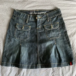 Jeanskjol från edc by Esprit, stl 34 - Mörkblå jeanskjol från edc by Esprit med coola fickor fram och bak, snygga kontrastsömmar och klassisk jeanslook. Kjolen är kort och har bälteshällor, knapp- och dragkedjestängning samt detaljerade ficklock. Perfekt för en avslappnad och trendig stil.